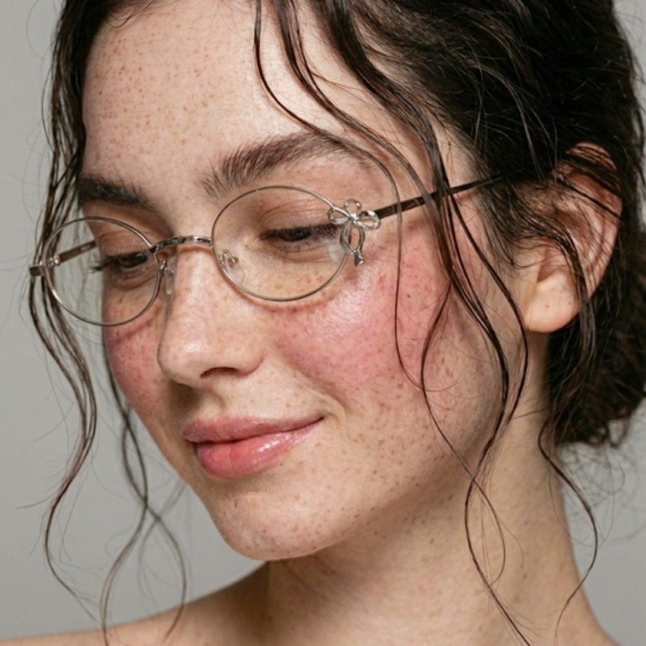 A close-up profile of a smiling girl featuring coquette eyeglasses frame in silver metal for casual daily scenario.