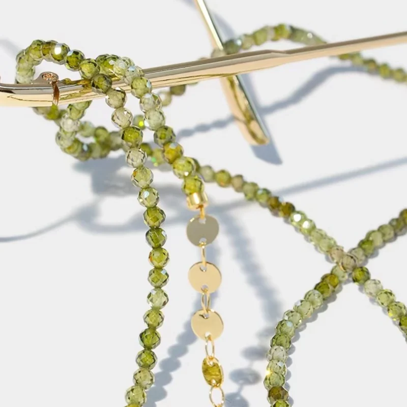 A beautiful close-up shot featuring an eyeglass chain in green zircon and 14k gold for reading glasses.